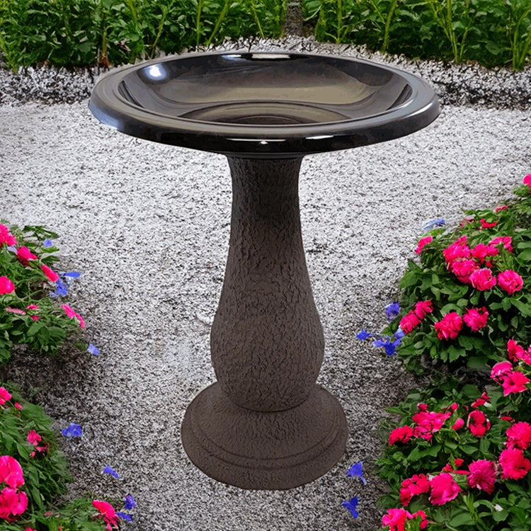 Bronze pedestal birdbath on garden path with pink flowers