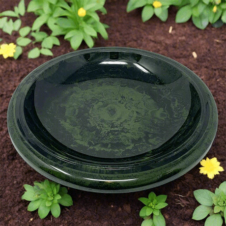 Hunter green birdbath bowl placed in a garden bed surrounded by flowers