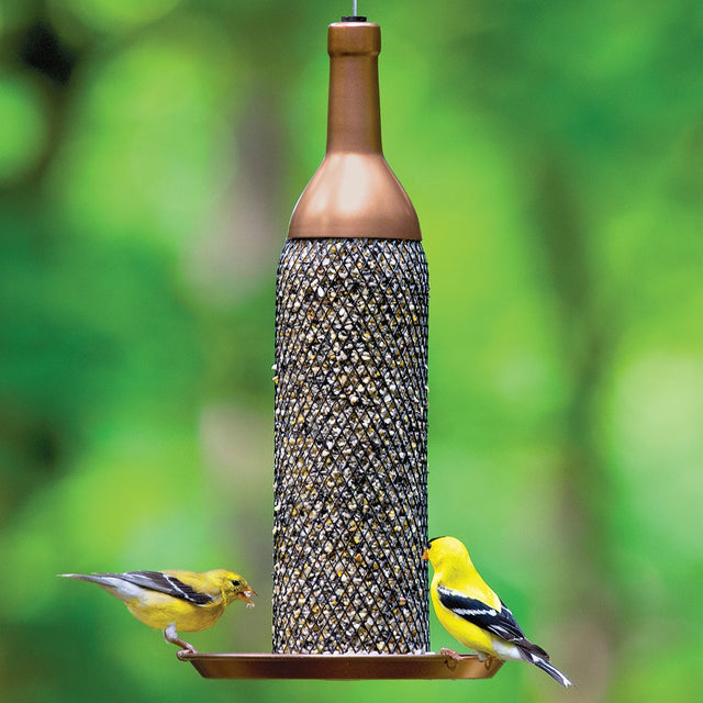 Mesh Wine Bottle Bird Feeder with copper finish, features a metal mesh tube filled with seeds, supporting two goldfinches on its tray.