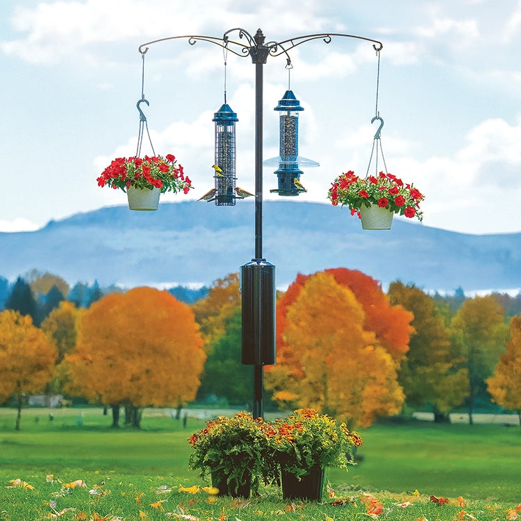 Brome Raccoon Buster® Guardian Pole System with multi-arm design, tubular feeders, and hanging planters in a scenic yard, ensuring raccoon-proof bird feeding.