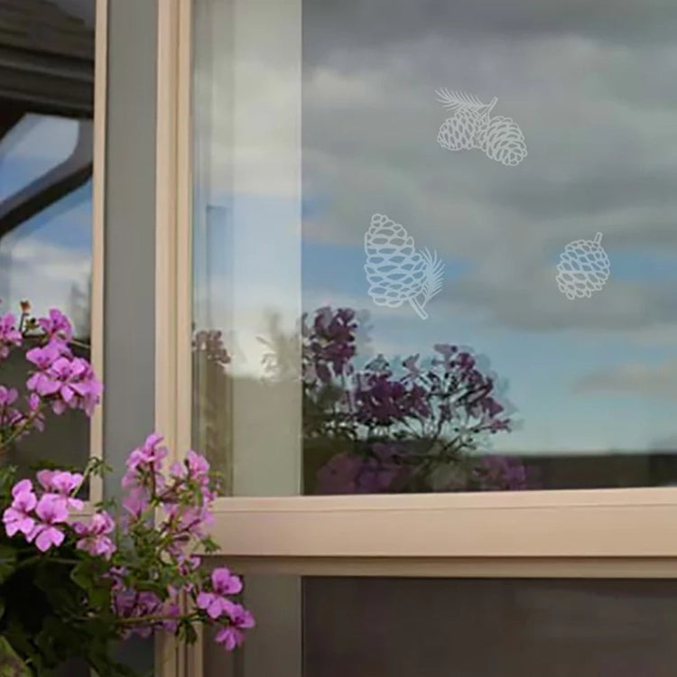 Window with decorative pine cone decals and purple flowers in the foreground