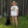 Butterflies of North America T-Shirt: Woman with sun hat standing beside a black dog in grass, holding a strap.
